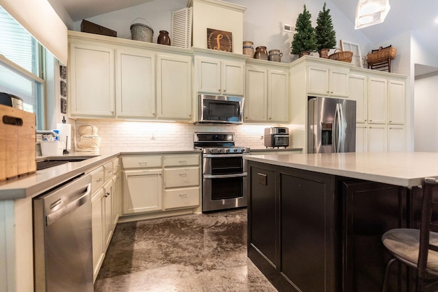 kitchen featuring sink, a kitchen breakfast bar, backsplash, vaulted ceiling, and appliances with stainless steel finishes