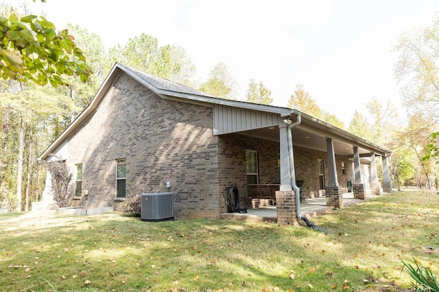 view of side of home with a yard, a patio, and central AC