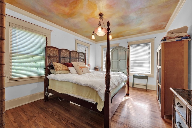 bedroom with hardwood / wood-style floors, ornamental molding, and multiple windows