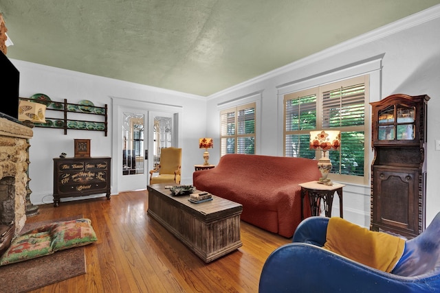 living room with french doors, ornamental molding, a textured ceiling, hardwood / wood-style flooring, and a fireplace