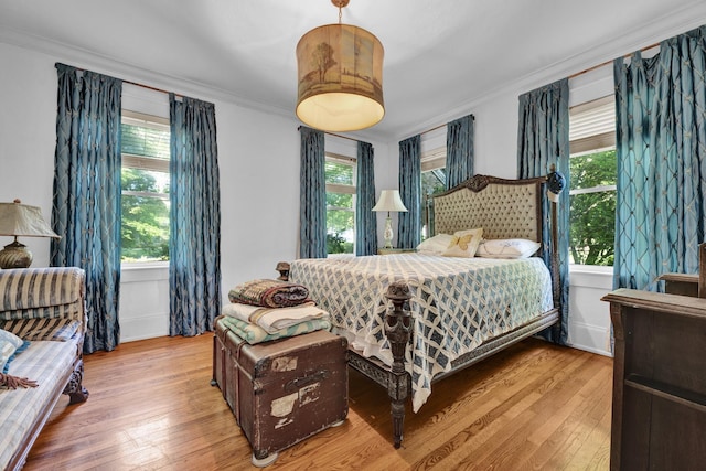 bedroom featuring light hardwood / wood-style floors, multiple windows, and ornamental molding