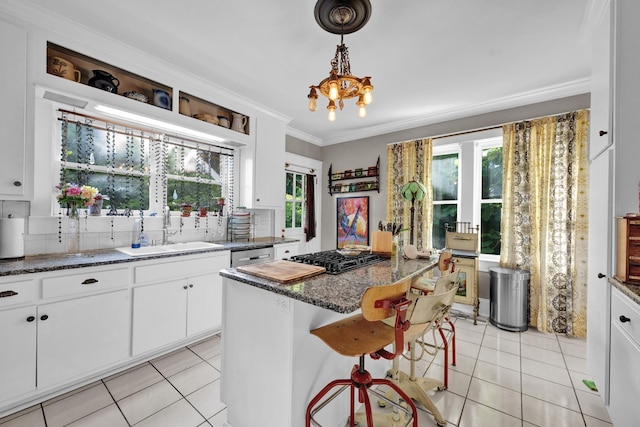 kitchen featuring a kitchen island, plenty of natural light, a breakfast bar area, white cabinets, and ornamental molding