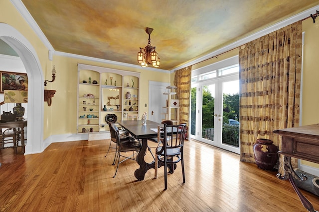 dining room featuring hardwood / wood-style flooring, a chandelier, crown molding, and french doors