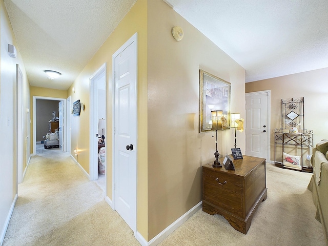 corridor with light carpet and a textured ceiling