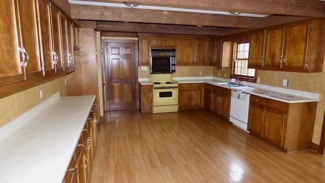  - kitchen featuring white appliances, brown cabinetry, wood finished floors, and beam ceiling
