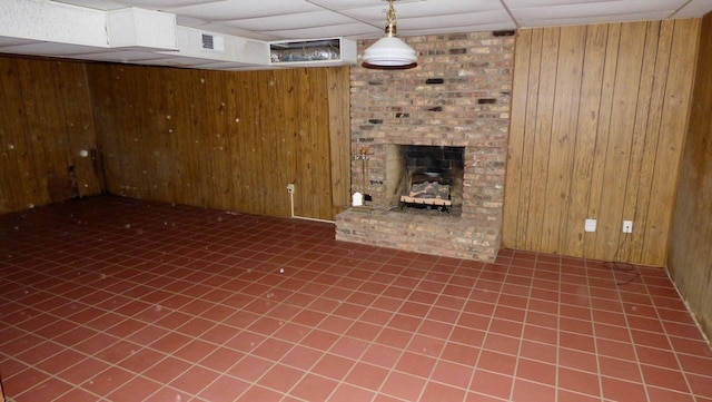  - unfurnished living room featuring wood walls, a fireplace, and tile patterned flooring
