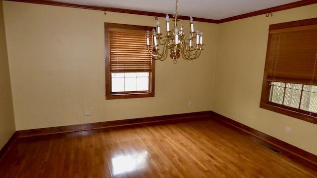  - spare room with wood finished floors, a chandelier, baseboards, plenty of natural light, and ornamental molding