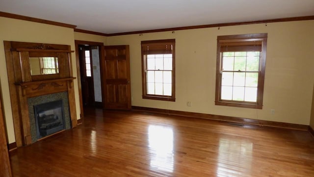  - unfurnished living room with wood finished floors, plenty of natural light, baseboards, and crown molding