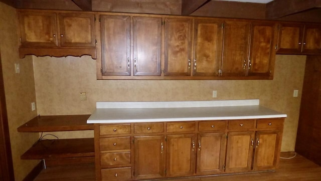  - kitchen featuring brown cabinetry, light countertops, and wood finished floors