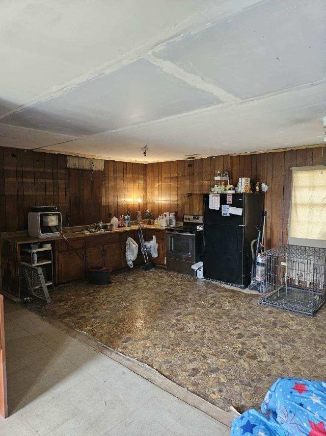  - kitchen with wood walls, range with electric stovetop, freestanding refrigerator, and tile patterned floors