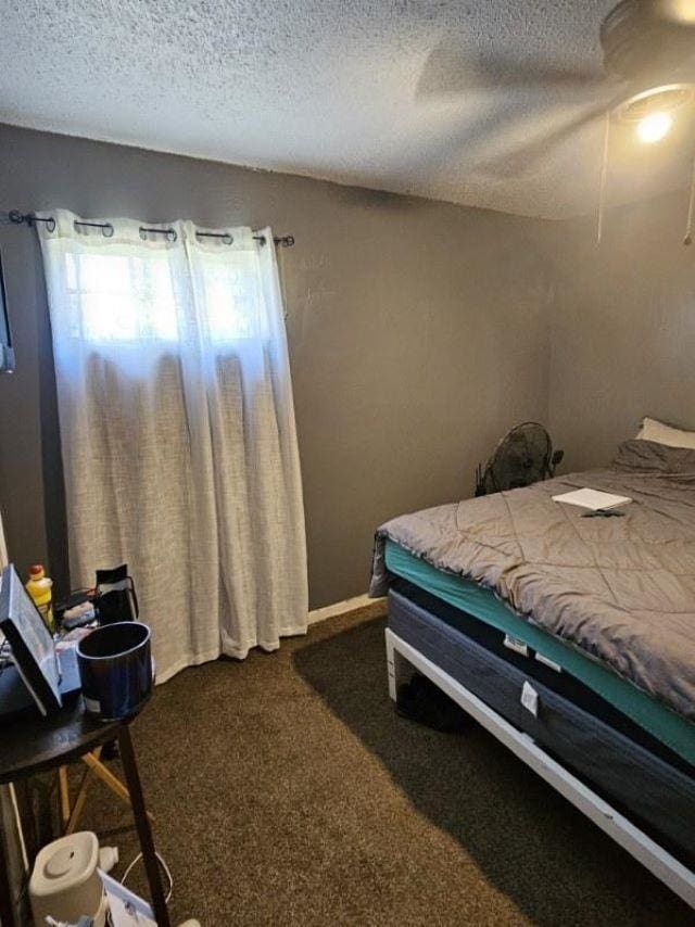  - bedroom featuring a textured ceiling, dark carpet, and a ceiling fan
