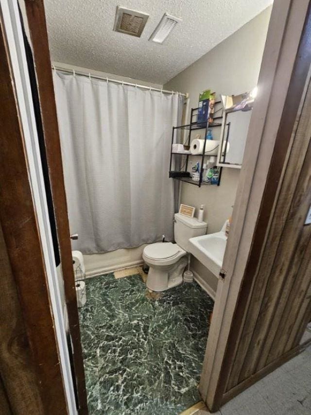  - full bathroom with toilet, a textured ceiling, a sink, and shower / bath combination with curtain
