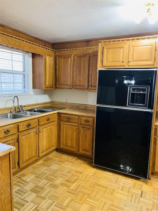 kitchen featuring light parquet floors, sink, a textured ceiling, and black refrigerator with ice dispenser