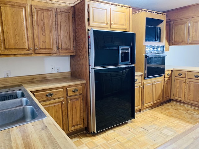 kitchen featuring light parquet flooring, sink, and black appliances