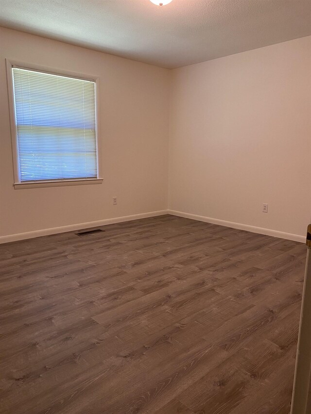  - spare room featuring dark wood-style floors and baseboards