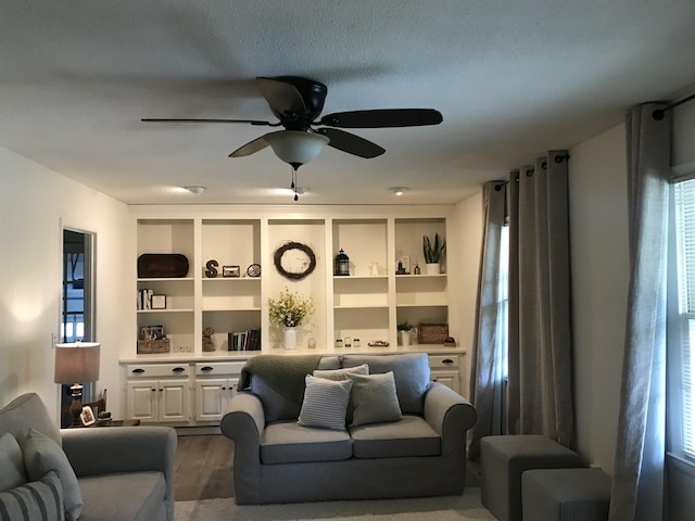  - living room with a ceiling fan, dark wood-type flooring, and built in features