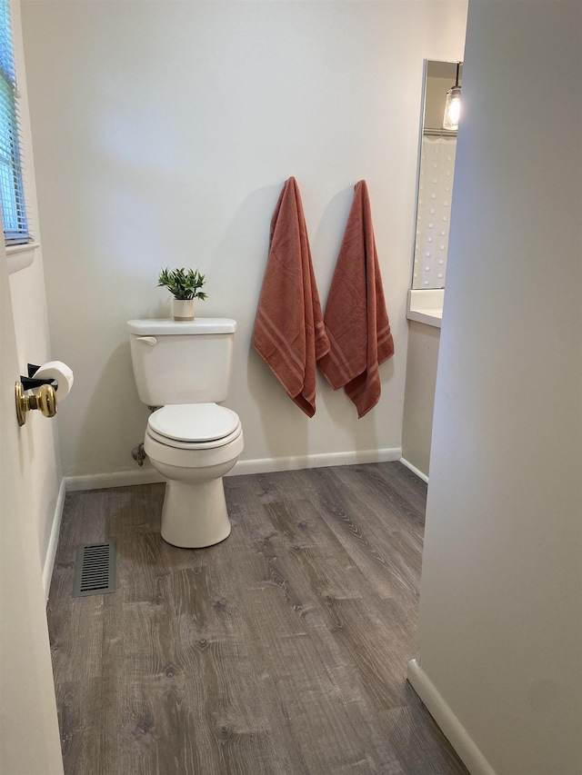  - bathroom featuring toilet, wood finished floors, and baseboards