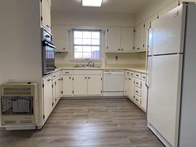  - kitchen featuring white appliances, heating unit, a sink, light wood-style floors, and white cabinetry