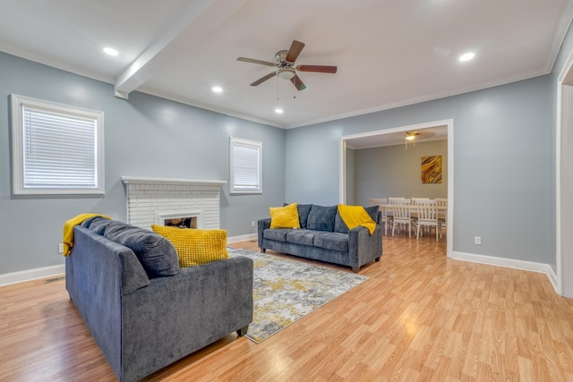 living room with beam ceiling, a brick fireplace, ornamental molding, and light wood-type flooring