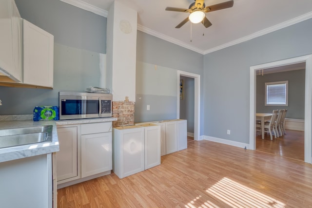 kitchen featuring white cabinets, light hardwood / wood-style floors, crown molding, and sink