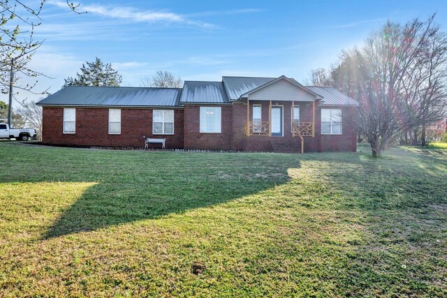  - view of front of house with a metal roof, brick siding, and a front yard