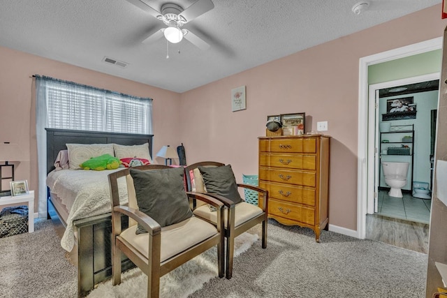  - carpeted bedroom featuring a textured ceiling, a ceiling fan, and ensuite bath