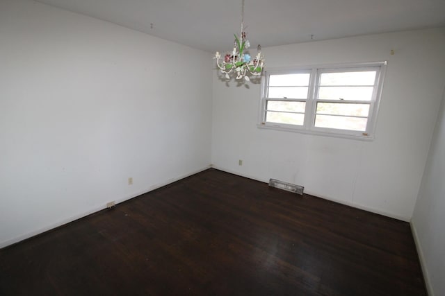 empty room featuring dark wood-type flooring and a chandelier