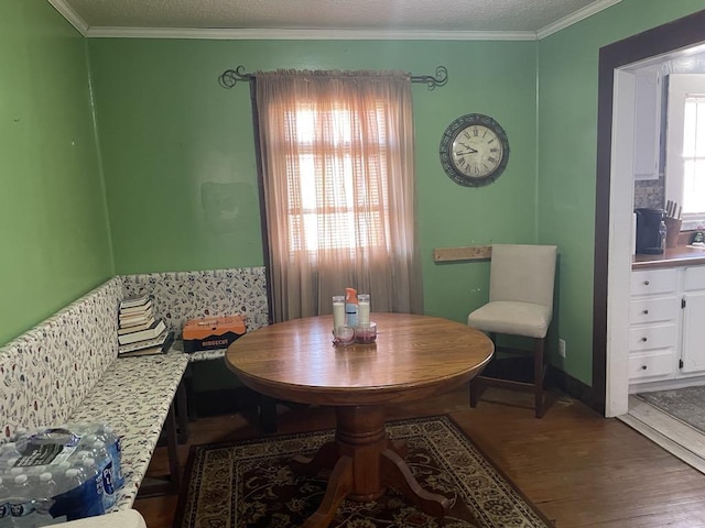 dining area with crown molding, wood-type flooring, a textured ceiling, and a healthy amount of sunlight