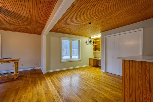 unfurnished dining area with ornamental molding, wooden ceiling, a chandelier, and light hardwood / wood-style flooring