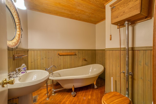 bathroom featuring sink, wood ceiling, hardwood / wood-style flooring, a tub, and wood walls