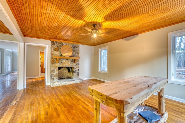 unfurnished dining area with crown molding, wooden ceiling, light wood-type flooring, ceiling fan, and a fireplace