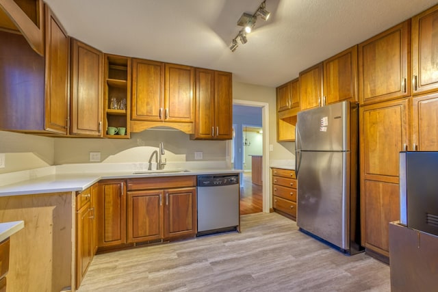 kitchen featuring stainless steel appliances, sink, a textured ceiling, and light wood-type flooring