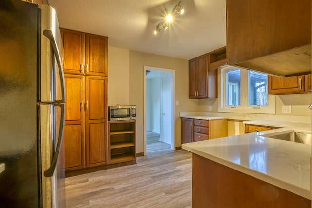 kitchen with refrigerator, sink, light hardwood / wood-style floors, kitchen peninsula, and a textured ceiling