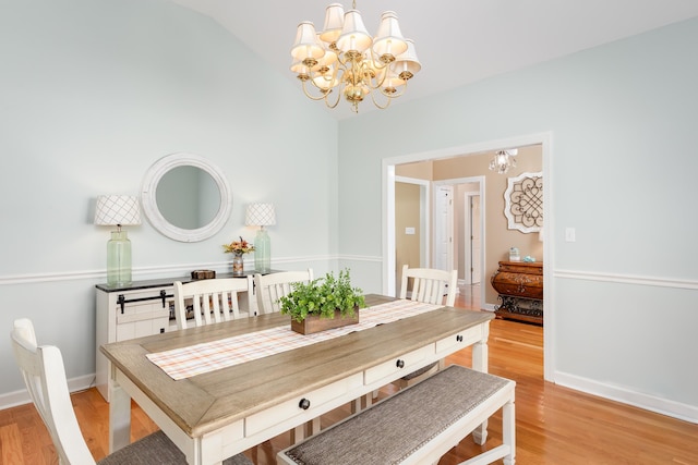  - dining area with light wood-type flooring, vaulted ceiling, and a notable chandelier