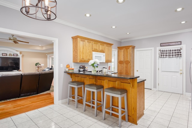  - kitchen featuring kitchen peninsula, crown molding, and light tile patterned floors