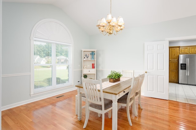  - dining area featuring plenty of natural light, light hardwood / wood-style flooring, vaulted ceiling, and a notable chandelier