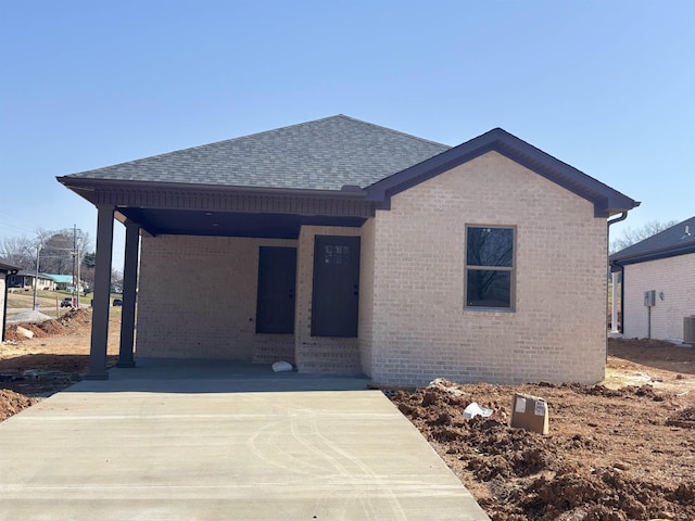 view of front of house with brick siding, central AC, and a shingled roof