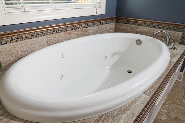 bathroom featuring stone tile flooring and a whirlpool tub