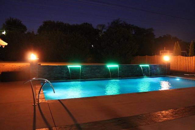 pool at night with a fenced in pool and fence