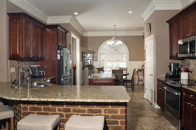 kitchen featuring an inviting chandelier, a peninsula, ornamental molding, a sink, and appliances with stainless steel finishes