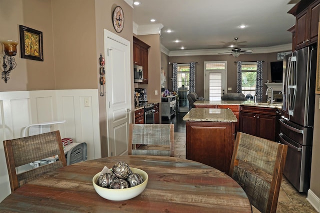 kitchen featuring a kitchen island, crown molding, appliances with stainless steel finishes, a peninsula, and a sink