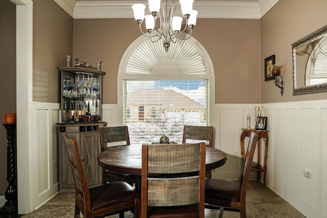 dining room featuring a chandelier, a decorative wall, wainscoting, and ornamental molding