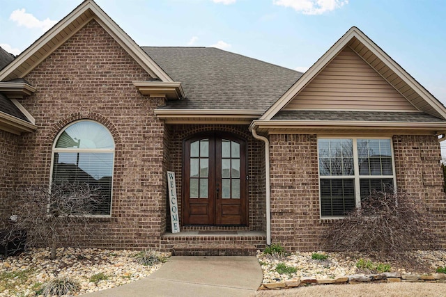 view of front of house with french doors, brick siding, and a shingled roof