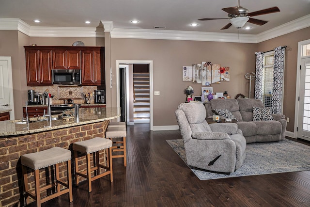 living room with baseboards, dark wood-style floors, a ceiling fan, and crown molding