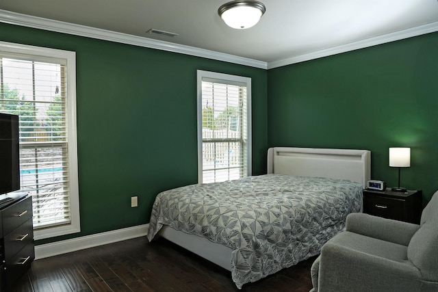 bedroom with dark wood-style floors, visible vents, baseboards, and ornamental molding