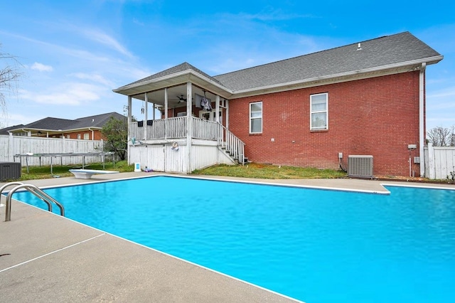 view of swimming pool featuring ceiling fan, a diving board, and cooling unit