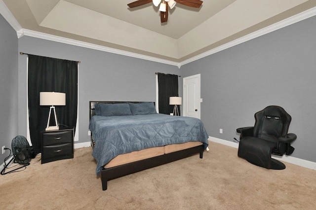 carpeted bedroom with a tray ceiling, ceiling fan, and crown molding