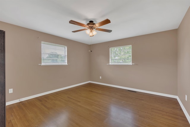  - spare room featuring plenty of natural light, a ceiling fan, baseboards, and wood finished floors