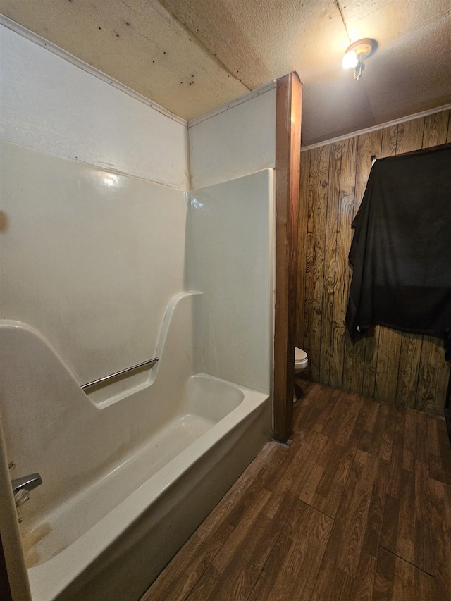 bathroom with hardwood / wood-style flooring, wooden walls, and toilet