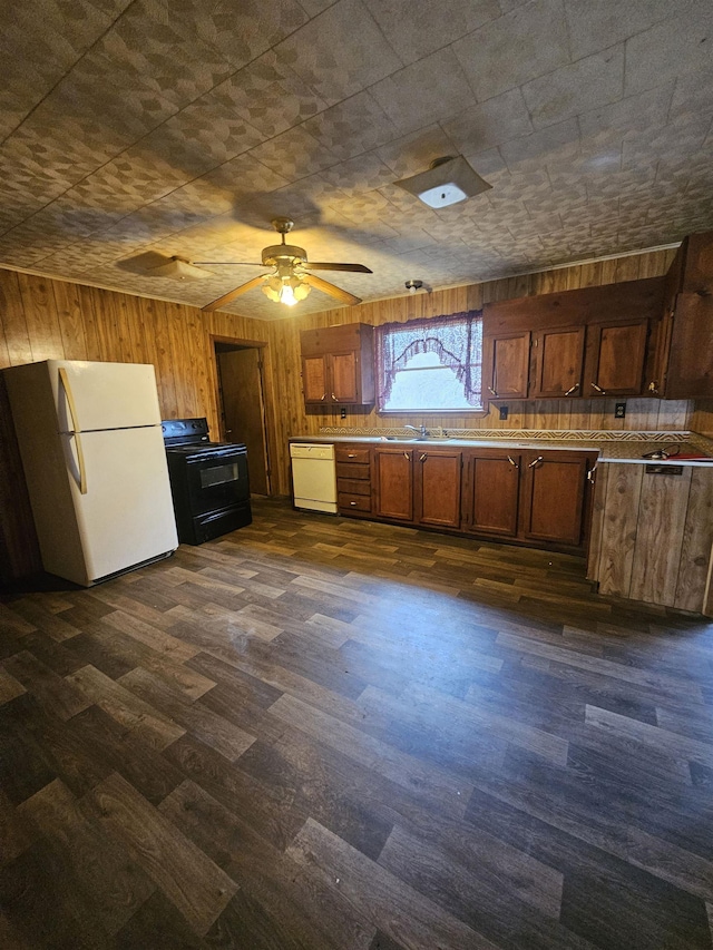 kitchen featuring dark hardwood / wood-style floors, wooden walls, sink, ceiling fan, and white appliances